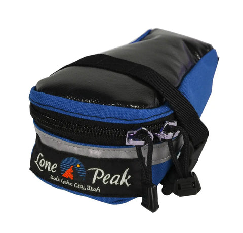 The Lone Peak Packs Tool Pouch Seat Bag is blue and black with a Salt Lake City logo, orange mountain graphic, and reflective strip—ideal for biking or storing tools.
