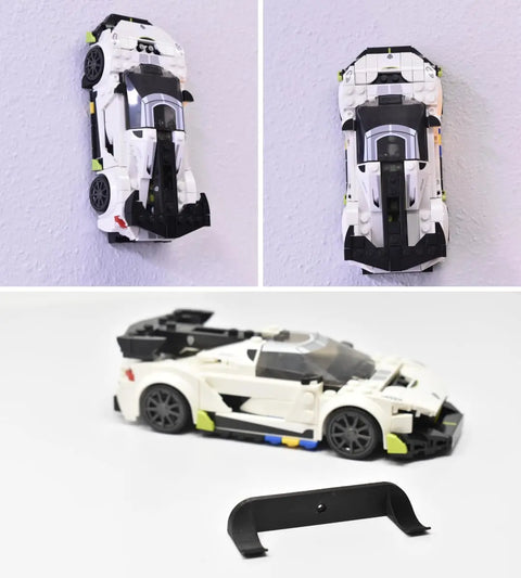 A Lego car model is shown mounted vertically on a wall using the Chatelet Manufacturing Low Profile Collectible Car Display Wall Mount (Black 3-Pack), and placed on a white surface beside an extra black mounting bracket.