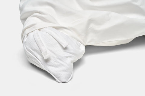 A close-up of the Cotton Duvet Cover Set by American Blossom Linens shows two corner fabric ties, partially enclosing a pillow or insert, highlighting its quality craftsmanship on a plain white background—ideal for luxury bedding seekers.