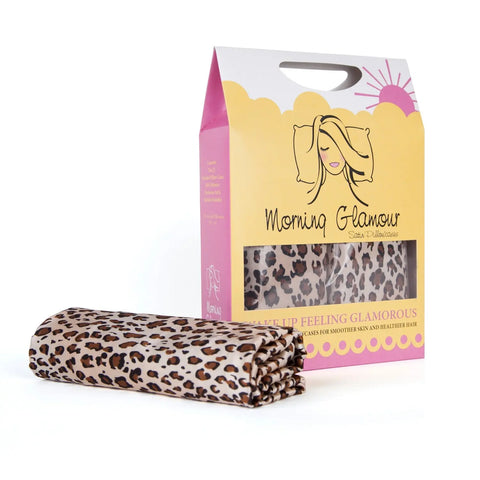 A folded standard/queen satin pillowcase from Morning Glamour is shown in front of its packaging, which has a cartoon woman and a window displaying the frizz-reducing pillowcase. Sold as a 2-pack with multiple print options.
