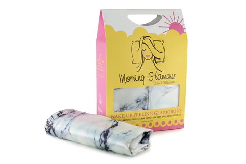 A package of Morning Glamour Satin Pillowcase Standard/Queen 2PK (Multiple Print Options) sits beside a folded satin pillowcase with a marble-like design—ideal for anyone seeking silky pillowcases to help reduce frizz.