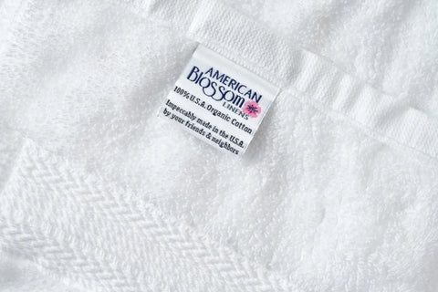 Close-up of a white Bathroom Washcloth made of luxury USA cotton by American Blossom Linens, featuring a label. Impeccably crafted in the USA for exceptional absorbency—a perfect addition to your self-care ritual.