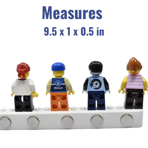 Four minifigures stand on a white Chatelet Manufacturing Collectibles Display Fridge Magnet compatible with Lego minifigures. Each figure has unique hair and outfits. Measures 9.5 x 1 x 0.5 in; display figurines on your fridge or metal surfaces. Made in USA.