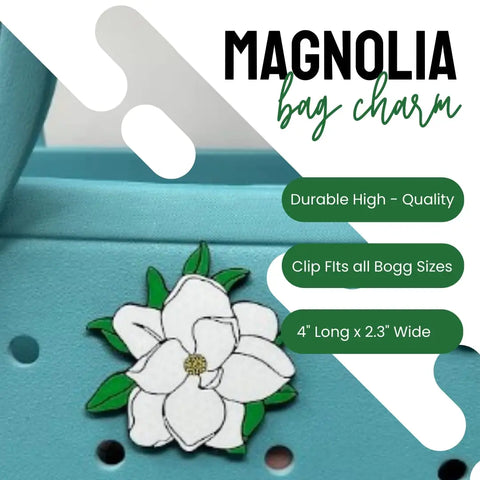 A white Chatelet Manufacturing Baglets - Magnolia Charm decorates a light blue tote. Features include high durability, universal clip for Bogg and Simply Southern bags, and a 4” x 2.3” size. Title: Magnolia decorative bag accessory.