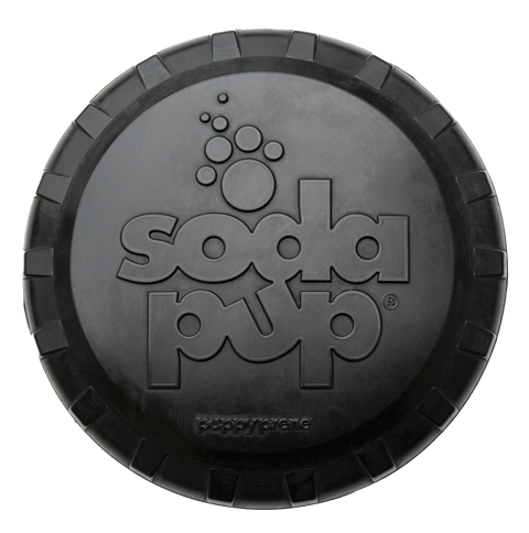 The SodaPup Magnum Bottle Top Flyer is a large, round black frisbee made of ultra-durable magnum compound natural rubber, with an embossed SodaPup, paw print design, and a textured, segmented edge.