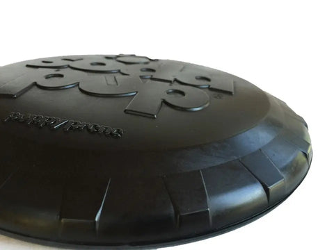 Close-up of a black SodaPup Magnum Bottle Top Flyer, an ultra durable large rubber retrieving frisbee, shown against a white background.