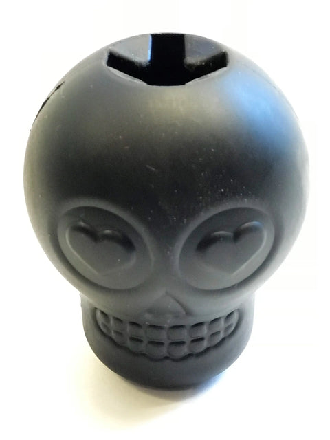 The SodaPup Magnum Sugar Skull EDispenser is a black, ultra-durable chew toy and treat dispenser shaped like a skull with heart-shaped eyes and a grinning mouth, shown against a plain white background.