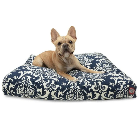 A light brown French Bulldog lies on the Majestic Pet French Quarter Rectangle Dog Bed, featuring a navy blue and white patterned, removable cover, looking toward the camera.