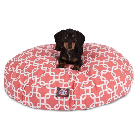 A small black and brown dachshund lies on the Majestic Pet Links Round Dog Bed, featuring a white interlocking geometric pattern and a soft pink washable, removable cover.