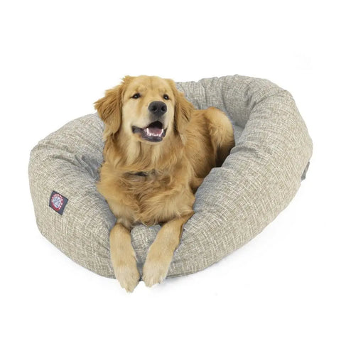 A golden retriever lounges happily with its mouth slightly open in the Majestic Pet Palette Heathered Bagel Dog Bed, a light gray, oval bed featuring textured, water-resistant fabric and excellent spine support.