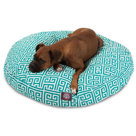 A brown dog is lying on the Majestic Pet Towers Round Dog Bed, which features a teal and white geometric design and a removable, washable cover.