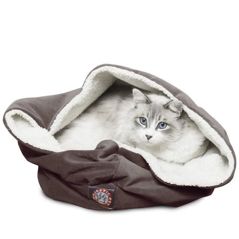 A fluffy white and gray cat with blue eyes relaxes inside the Majestic Pet Suede Burrow Cat Bed, which features a soft sherpa interior. The cat peeks out from the bed’s cozy, inviting opening.