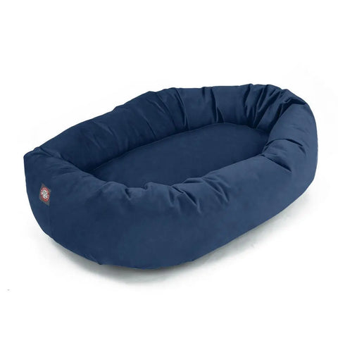 The Majestic Pet Suede Bagel Dog Bed is a large, oval bed with raised cushioned sides, dark blue polyester faux suede cover, and a small logo patch on one end.