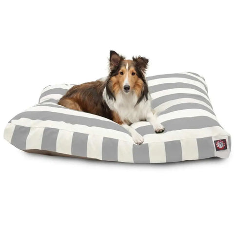A brown, black, and white dog is lying on the Majestic Pet Vertical Stripe Memory Foam Dog Bed, a large, rectangular bed with gray and white stripes and a small branded tag in the corner.