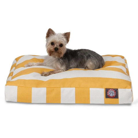 A small Yorkshire Terrier rests on the Majestic Pet Vertical Stripe Memory Foam Dog Bed, which features a washable, removable yellow and white striped cover with a sewn-on label in one corner for easy cleaning.