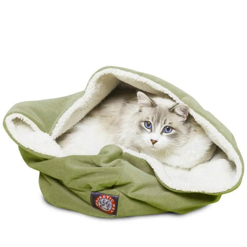 A fluffy white and gray cat with blue eyes relaxes inside the Villa Burrow Cat Bed by Majestic Pet, a soft green and white fleece pouch with faux suede details and a brown paw-print patch—perfect for feline comfort.