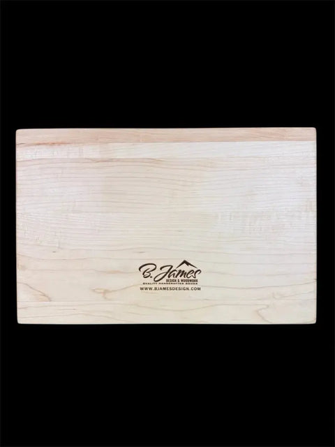 The Grizzly Inlay Serving Board by B. James Design & Woodwork, handcrafted from solid maple and engraved with the brand logo and website at the center, is showcased on a solid black background.