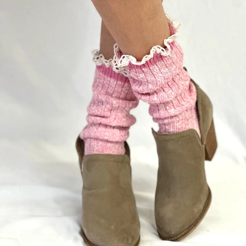 A close-up of a persons lower legs wearing Catherine Cole MARLED Cotton Short Lace Boot Socks - Pink and taupe suede ankle boots with wooden heels, standing on a white surface.
