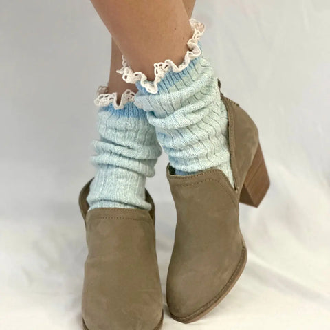 A person wearing Catherine Cole MARLED Cotton Short Lace Boot Socks in Carolina Blue and tan suede ankle boots with a low chunky heel, posing with legs crossed against a plain white background.