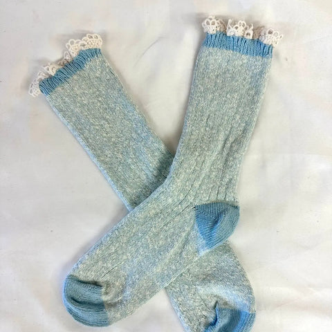 The Catherine Cole MARLED Cotton Short Lace Boot Socks in Carolina Blue are light blue with white lace trim at the cuffs, shown laid out in an X shape on a white background.