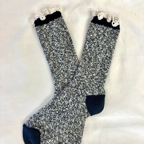 The Catherine Cole MARLED Cotton Short Lace Boot Socks in Navy feature black and white marled cotton with navy toes, heels, and cuffs, plus white lace trim at the top, displayed crossed on a white surface.