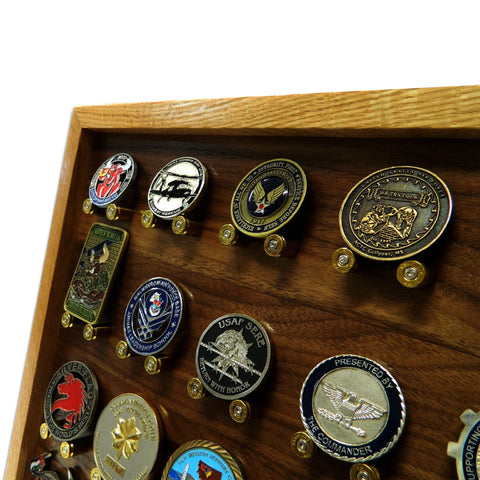 A close-up of The ORIGINAL Brass Casing Challenge Coin Display - Medium by Legacies of America Woodworking Company, holding several uniquely designed coins and badges, against a plain white background.