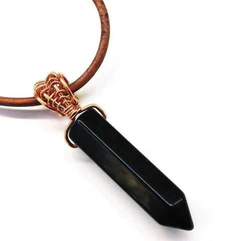 The Mens Rustic Wire Wrapped Pointed Gemstone Crystal Leather Necklace by Alexa Martha Designs features a black gemstone point pendant intricately wire wrapped in copper, displayed against a white background.