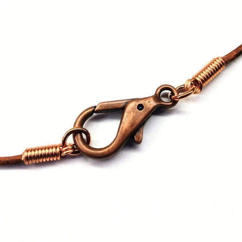 Close-up of a copper lobster clasp with wire-wrapped connectors on a brown leather cord, from the Alexa Martha Designs Mens Rustic Wire Wrapped Pointed Gemstone Crystal Leather Necklace, shown against a white background.