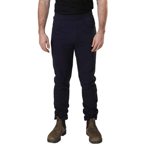 A person wearing Spiritex Saratoga Pants and brown Chelsea boots stands against a white background, with only their body from the shoulders down visible.