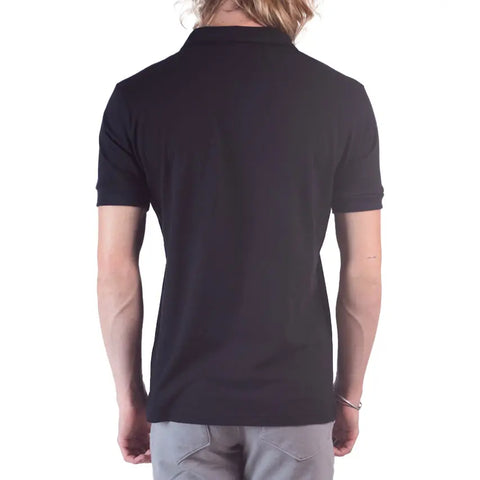 A person with long, light hair is seen from behind wearing the Spiritex Short Sleeve Mt. Mitchell Collared Shirt in black, paired with light gray pants, standing against a white background.