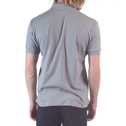 A person with long, light hair is seen from the back wearing a Spiritex Short Sleeve Mt. Mitchell Collared Shirt in light gray organic cotton and black pants, set against a plain white background.