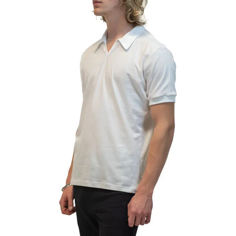 A person with wavy blond hair wears the Spiritex Short Sleeve Mt. Mitchell Collared Shirt and black pants, standing against a plain white background and facing slightly to the left.
