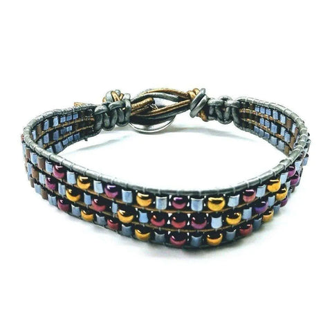 The Mens Tree of Life Intricately Beaded Leather Wrap Bracelet by Alexa Martha Designs features handmade earth-tone leather with three rows of metallic silver, gold, and magenta square and round beads, secured with a loop and knot closure.