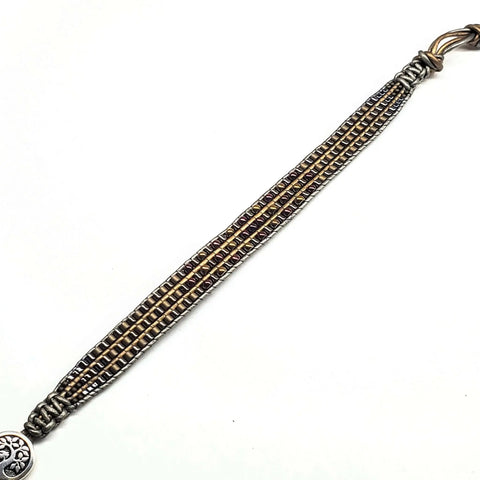 The Mens Tree of Life Intricately Beaded Leather Wrap Bracelet by Alexa Martha Designs features dark leather strands, metallic beads, and a round silver tree of life button clasp for a stylish, earthy, handcrafted look.