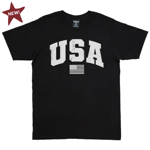 The Proudly USA Team USA Mens Cotton T-Shirt (Black) features bold white “USA” text with a distressed look, an American flag graphic, and is made from American grown cotton. A red “NEW!” star appears in the top left corner.
