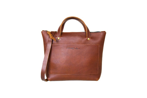 The Urban Southern Quinn Crossbody is a premium leather handbag featuring a front pocket, short handles, detachable shoulder strap, and zipper closure, shown against a plain white background.