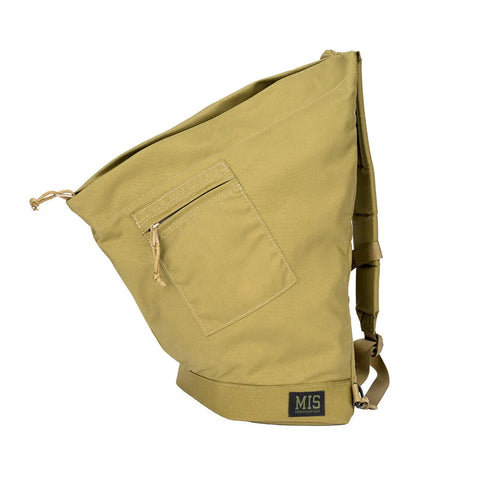 The MIS TA One Shoulder Bag in Coyote Tan features an asymmetrical design, front zip pocket, adjustable strap, and brand logo patch near the base. Made in the USA, its shown against a white background.