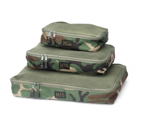 The MIS Organizer Set - Woodland Camo includes three rectangular, water-resistant Cordura nylon packing cubes with mesh tops, zipped closures, and MIS labels, stacked by size and featuring a green camouflage pattern.