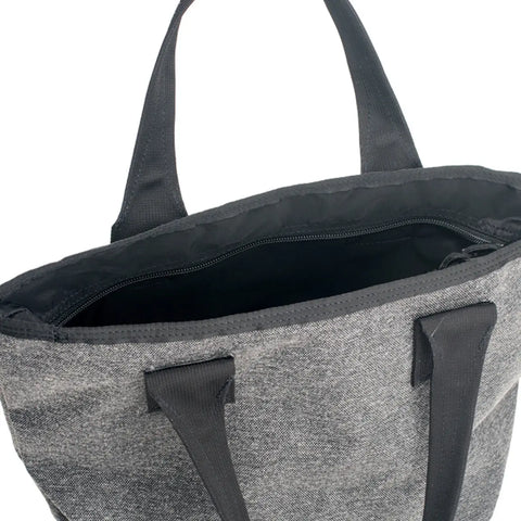 A close-up of the MIS Mini Tote Bag - Denim Grey, crafted from water-resistant Cordura nylon with black handles and a top zipper, reveals its durable inner lining. This stylish tote offers both resilience and modern flair.