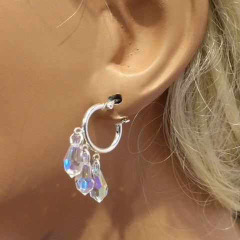 A close-up shows a person wearing Alexa Martha Designs’ Sterling Silver Hoop Sparkly Crystal Drop Dangle Earrings with three iridescent crystal beads, their light blonde hair highlighting these stunning handmade earrings.