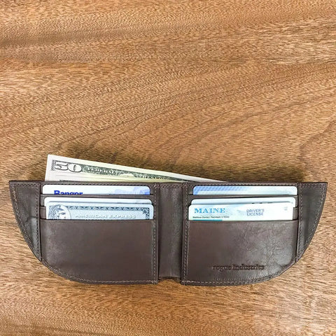 A Nantucket Bison Leather Front Pocket Wallet by Rogue Industries, shown open on a wooden surface, holds cards, a Maine driver’s license, and a folded fifty-dollar bill.