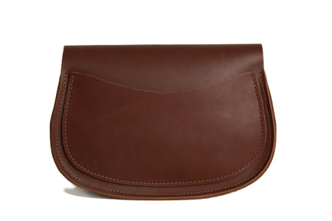 The Urban Southern Half Moon Crossbody is a minimalist brown leather handbag with a curved flap and visible stitching, displayed on a plain white background.