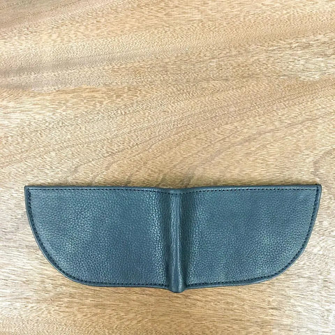 A green, textured Nantucket Front Pocket Wallet by Rogue Industries lies open and flat on a light wooden surface, forming a semicircular shape.