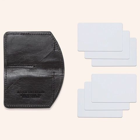 The Minimalist Wallet by Rogue Industries, crafted in black leather with curved edges, is open to reveal two card slots. To the right, six blank white cards are displayed in two overlapping rows of three.