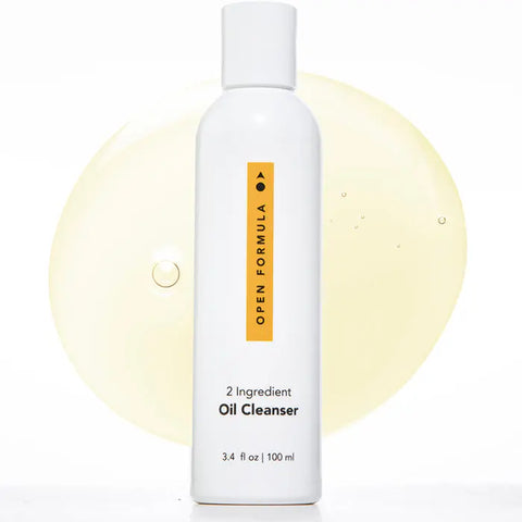 The Open Formula Oil Cleanser is a white, minimalist 3.4 fl oz (100 ml) bottle shown against a yellow oil smear. This pore-cleansing oil removes makeup effectively with no oily residue left behind.