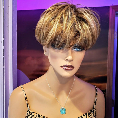 A mannequin with blue eyes and short blonde-brown hair, wearing a leopard-print top and the Mint Green Beaded Sterling Silver Clover Necklace by Alexa Martha Designs, is posed against a purple-lit background.