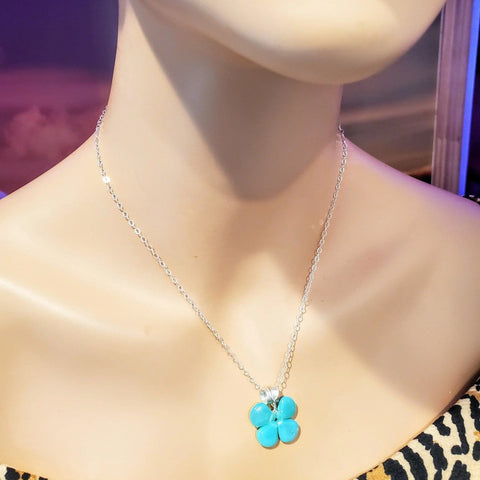 A mannequin displays the Alexa Martha Designs Mint Green Beaded Sterling Silver Clover Necklace, featuring a mint green four-leaf clover pendant, set against a blurred background.
