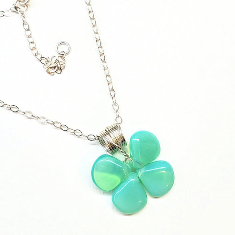 The Mint Green Beaded Sterling Silver Clover Necklace by Alexa Martha Designs showcases a four-petal flower pendant with smooth, mint green stones, reminiscent of a four-leaf clover, set against a white background.