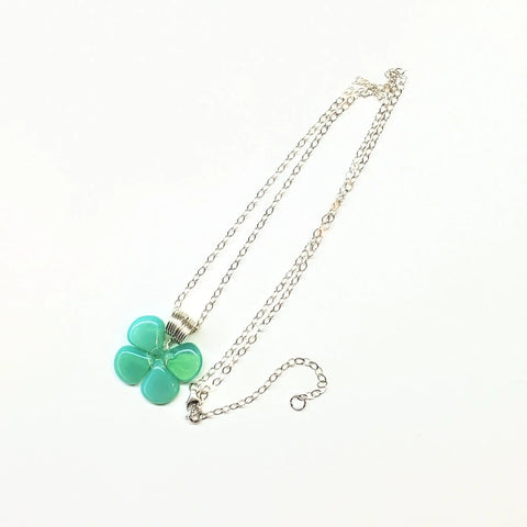 The Mint Green Beaded Sterling Silver Clover Necklace by Alexa Martha Designs features a four-leaf clover pendant with light teal and mint green glass beads in a floral design, shown on a white background.
