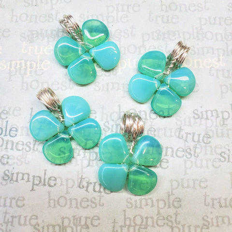 The Mint Green Beaded Sterling Silver Clover Necklace by Alexa Martha Designs is displayed against a background with words like true, honest, simple, and pure in soft gray and beige tones.